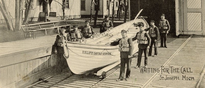 A photograph of the U.S. Life Saving Service crew posing with its surfboat in front of U.S. Life-Saving Station at St. Joseph, Michigan.