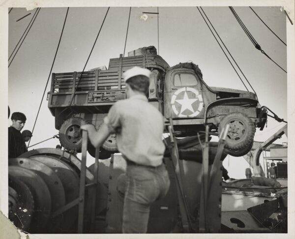 Photo: Coast Guardsmen swing an Army truck overside.