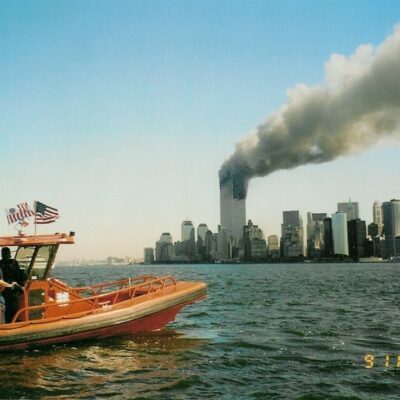 Photo: A Coast Guard rigid-hull inflatable boat with World Trade Center burning in background.