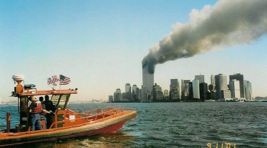 Photo: A Coast Guard rigid-hull inflatable boat with World Trade Center burning in background.