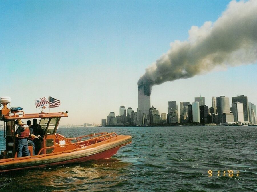 Photo: A Coast Guard rigid-hull inflatable boat with World Trade Center burning in background.