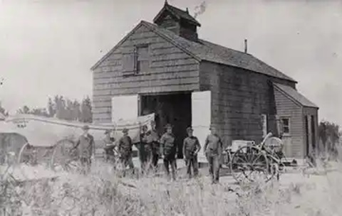 Photo: Crew with Lyle Gun, rescue, in front of barn-like building.