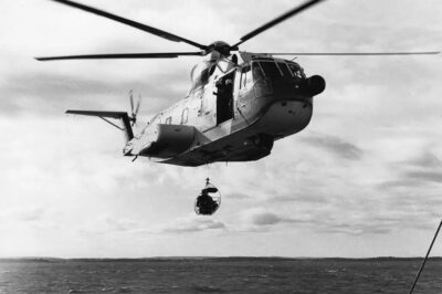 A vintage photo of a Coast Guard HH-3F “Pelican” making a hoist at sea.