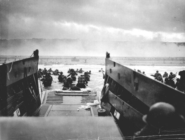 Photo: A view from above the ramp of a landing craft as soldiers race for the beach.