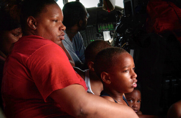 Photo: Survivors, pulled from their apartment building by a Coast Guard rescue swimmer, sit on the floor of an HH-65 Jayhawk