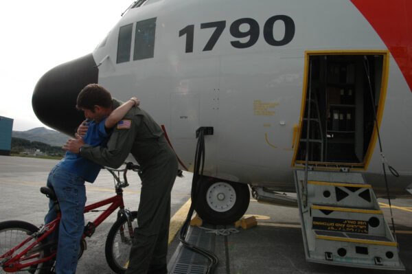 Photo: A Coast Guard aviation team member hugs his son beside a C-130.
