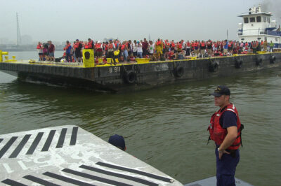 Photo: Cuttermen stands in the foreground while further away a barge carries refugees.