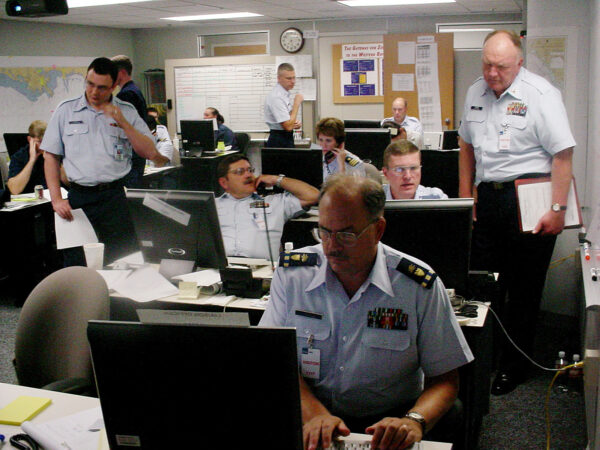 Photo: The Hurricane Katrina response center: a room with several phones, computer workstations, and people busy providing response support.
