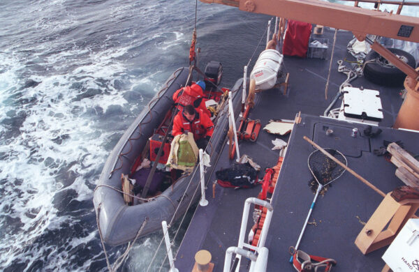 Photo: Crewmembers move recovered wreckage from their inflatable boat to the deck of a cutter.