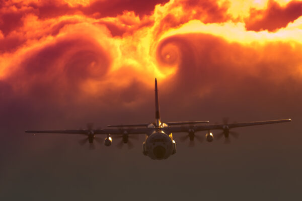 Photo: A C-130J passes the through glowing swirling red clouds.