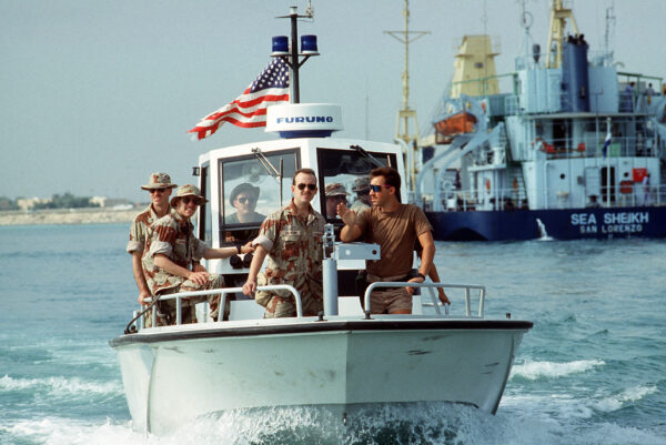Photo: Front view of members of PSU 302 (Cleveland, Ohio) patroling the harbor aboard a Navy patrol. In the background is the short and vessel Sea Sheikh.