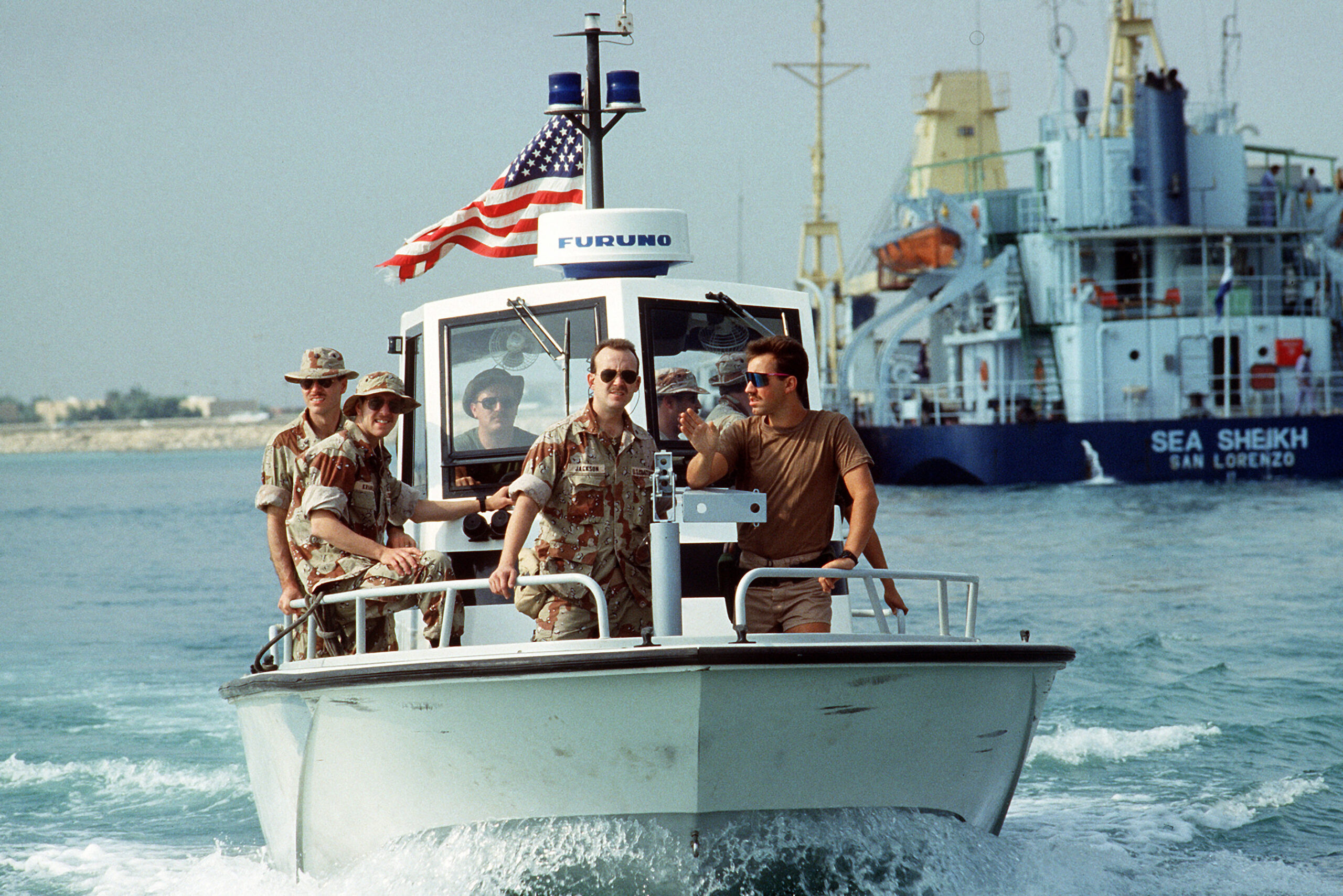 Photo: Front view of members of PSU 302 (Cleveland, Ohio) patroling the harbor aboard a Navy patrol. In the background is the short and vessel Sea Sheikh.