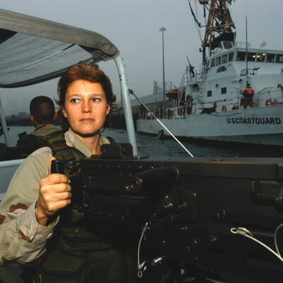 Photo: Boatswain's Mate Zora Tate stands behind her gun while her boat patrols the water around the USCGC Adak.