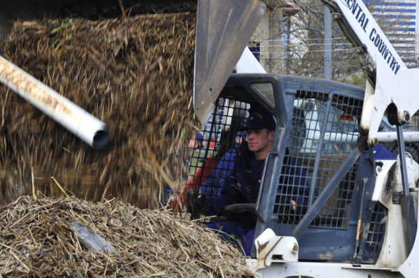 Photo: Coast Guardsman drives a compact excavator dumping debris.
