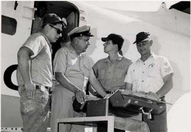 Photo: MCPOCG Calhoun looks at a tool chest with Coast Guardsmen next to an airplane.