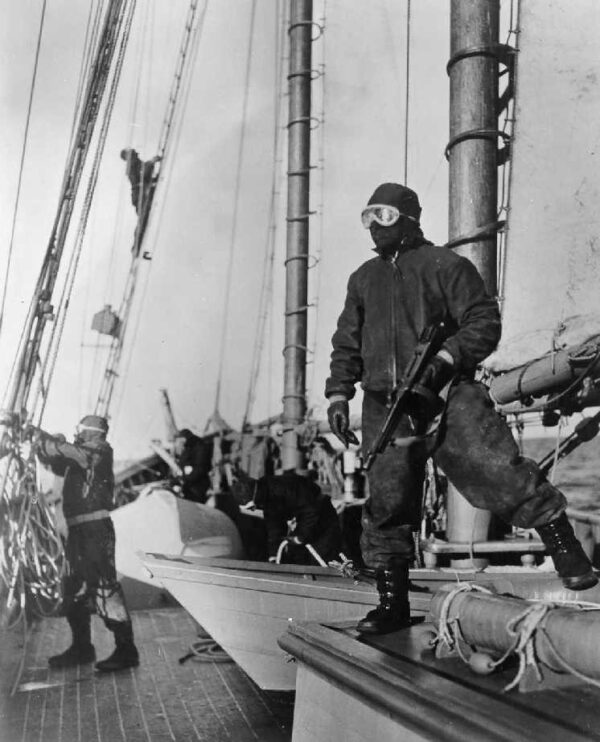 Photo: men with sailboat wearing goggles and holding a tommy gun.