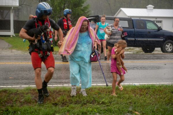 Photo: a helicopter crew walks with residents during an evacuation.