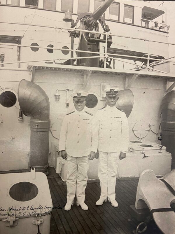 Photo: Two men in white uniforms standing on the deck of a cutter.