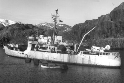 Photo: Storis displaying her deck and anti-aircraft guns, faded ice camouflage hull paint, as well as depth charge racks and a Grumman J2F “Duck” amphibian aircraft.