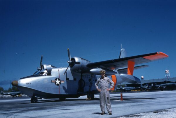 Photo: LTJG Bobby Wilks posing in front of an HU-16E “Albatross” fixed-wing amphibian aircraft.