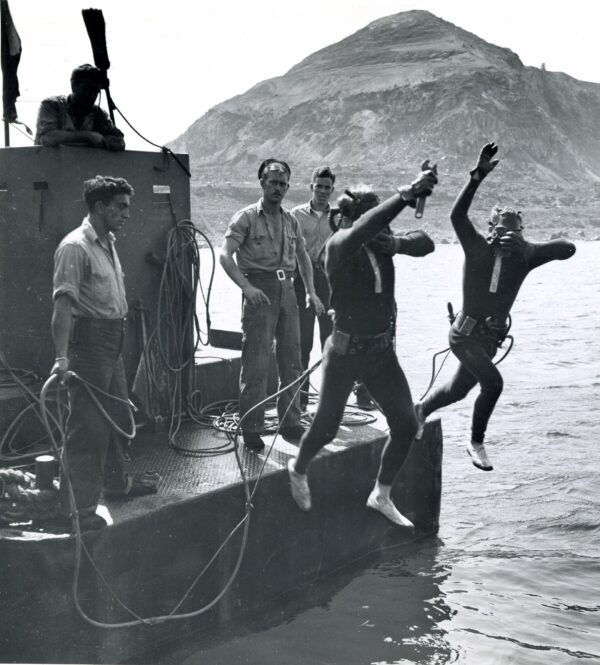 Photo: Divers with hoses jump into the water.
