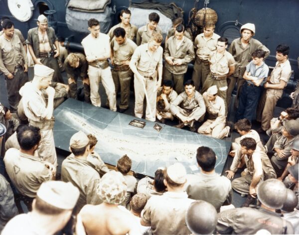 Photo: Marines stand around a large topographic map during a briefing.