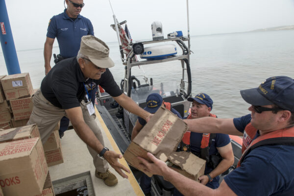 Photo: Crewman hands boxes to man on the dock.