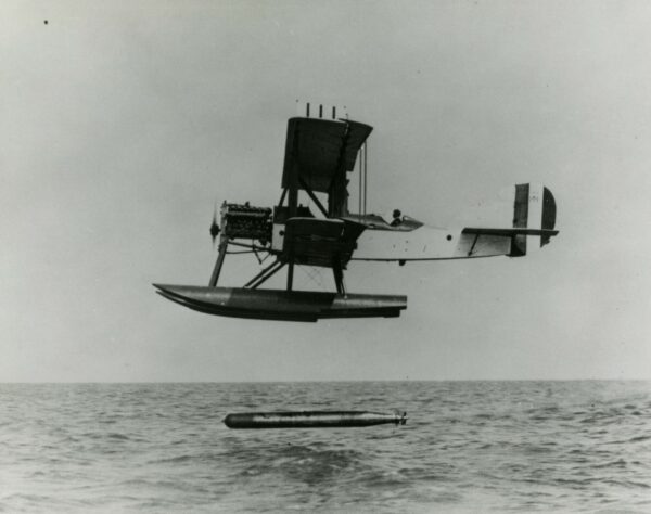 Photo: In profile, a Curtis R-6 float plane releasing a torpedo into the sea.