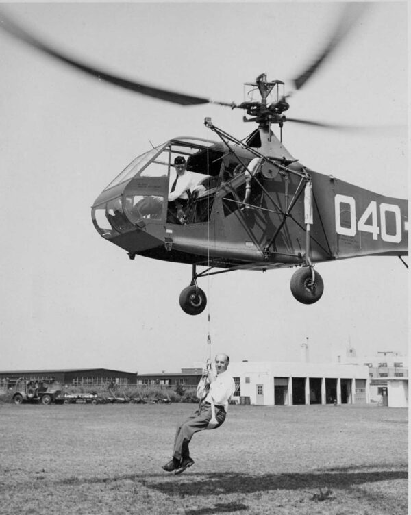 Photo: Igor Sikorsky seated in a sling, dangles from a helicopter hoist.