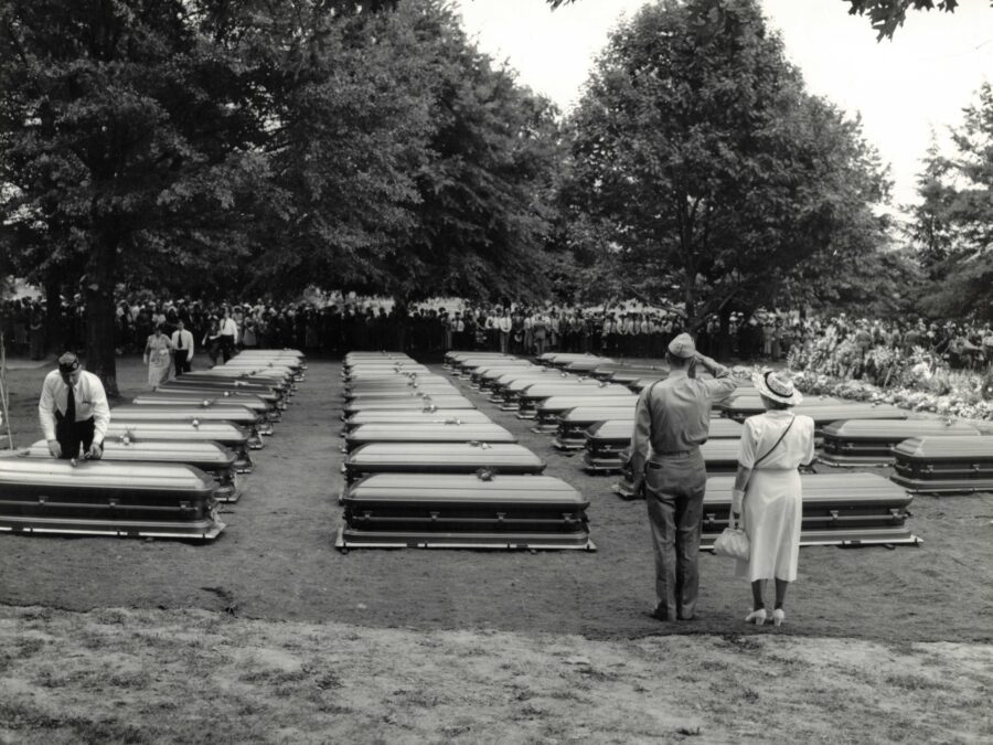 Photo: Caskets lined up with attendees.