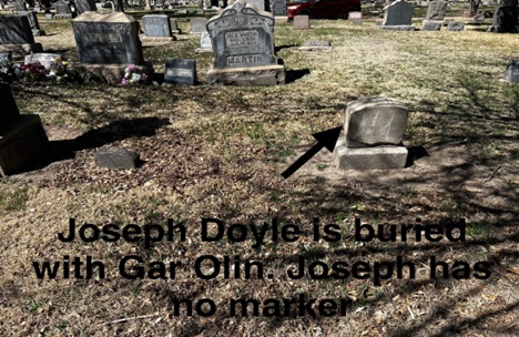 Photo with superimposed text: A grave stone and an arrow pointing at it, with the caption “Joseph Doyle is buried with Gar Olin. Joseph has no marker”.