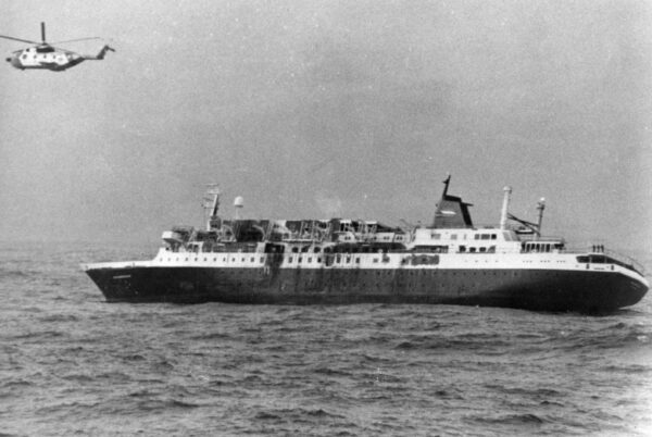 Photo: Prinsendam listing to starboard with a Coast Guard HH-3 helicopter hovering overhead.