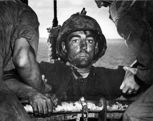 Photo: A marine looks into the camera as he is help on board.