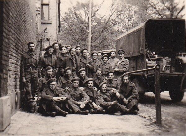 Photo: A group of men, some sitting, pose on sidewalk.