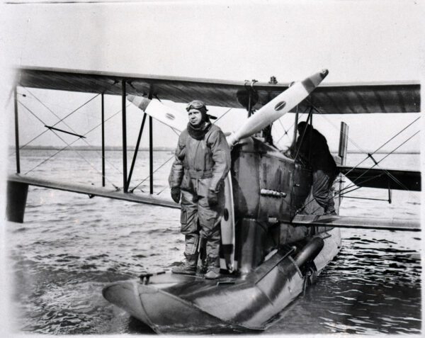 Photo: A pilot poses next to the propeller of his flying boat.