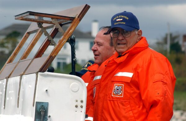 Photo: Two men in orange Coast Guard jackets stand at the helm.