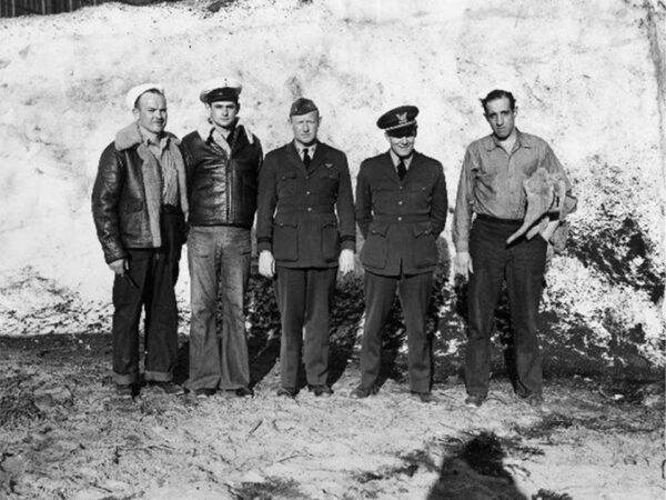 Photo: Five men in various uniforms pose next to a wall.