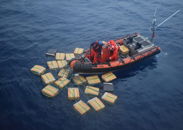 Photo: A boat crew pull together bales that are floating in the water.