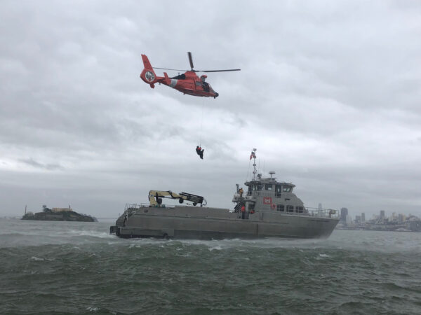 Photo: Distant starboard view of canine hoisting to helicopter.