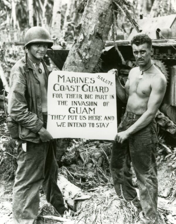 Photo: Two Marines hold a sign thanking the Coast Guard. Text on the sign reads