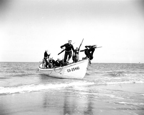 Photo: Armed sailors and dogs jump from their boat onto the beach.