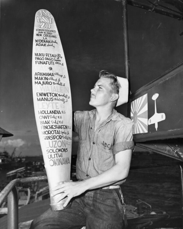 Photo: A Coast Guardsman aboard Coast-Guard-manned LST-20 shows a propellor blade that lists all the campaigns he and his LST have participated in in the Pacific.
