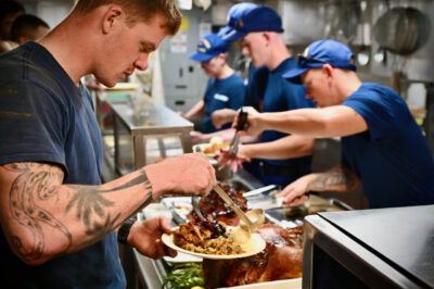 A seaman serves himself turkey and fixings in the galley.