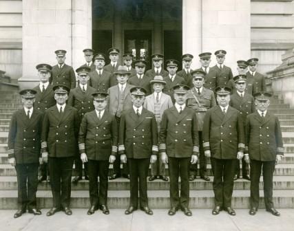 Photo: Formation of uniformed men posing on building steps.