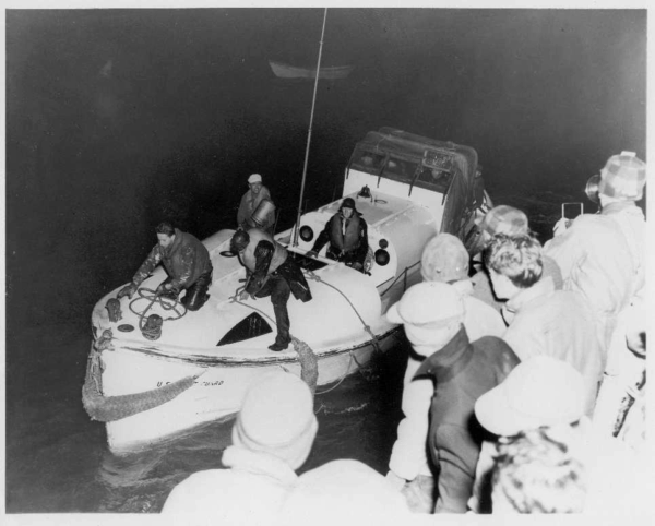 Photo: An overloaded lifeboat with a crowd looking on.