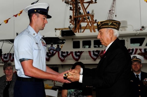 Photo: George Yered, father of Robert Yered, hands the long glass to Chief Petty Officer Stephen Kelly during the commissioning ceremony for Cutter Robert Yered.