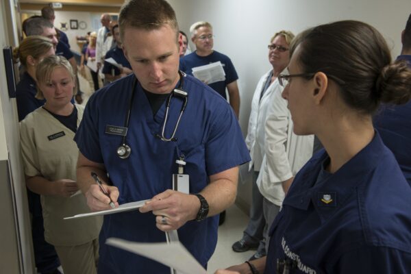 Photo: Doctor in a busy hallway reviews a chart.