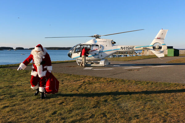 Photo: Santa walks away from helicopter with his sack of gifts.