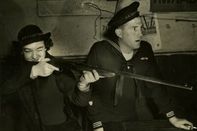 Photo: Seaman Marie Deppen aim rifle while Gunner's Mate looks on.