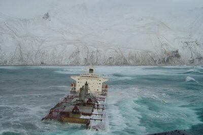 Photo: The Selendang Ayu sinking into icy water with snow-covered Unalaska Island in the background.